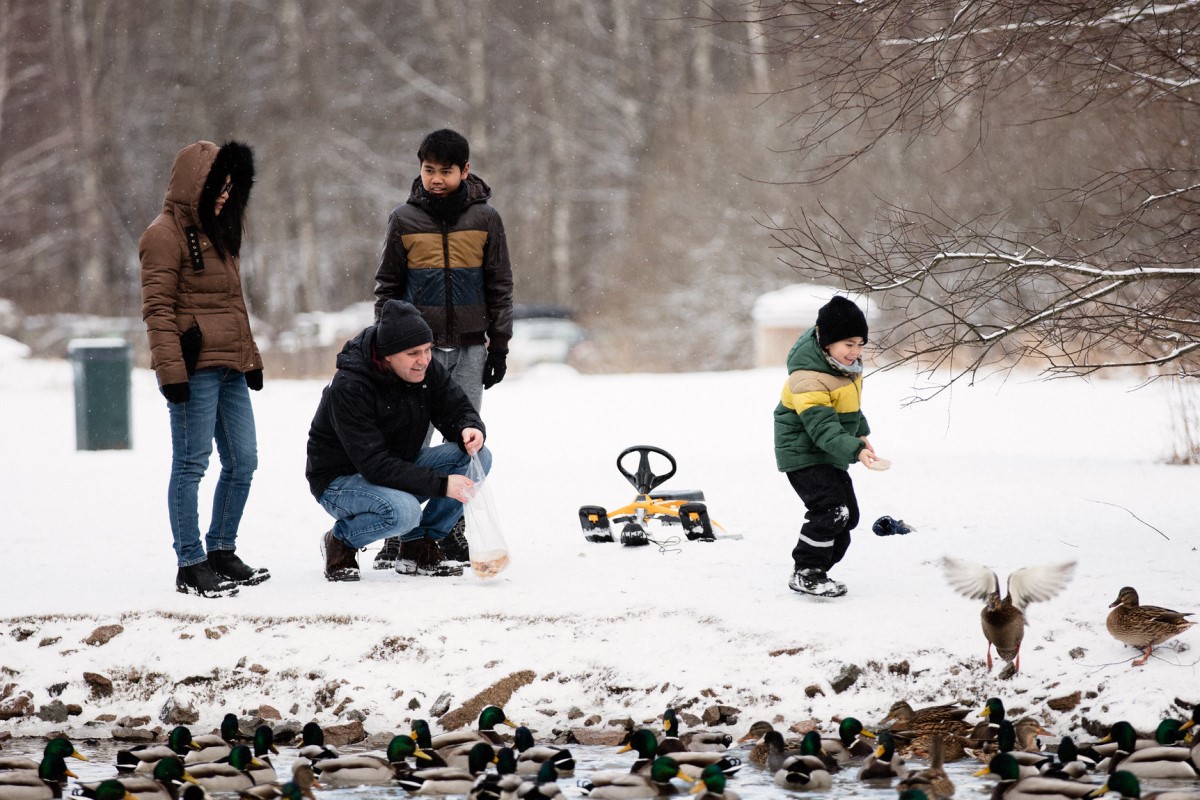 Familie som mater fugler i snø